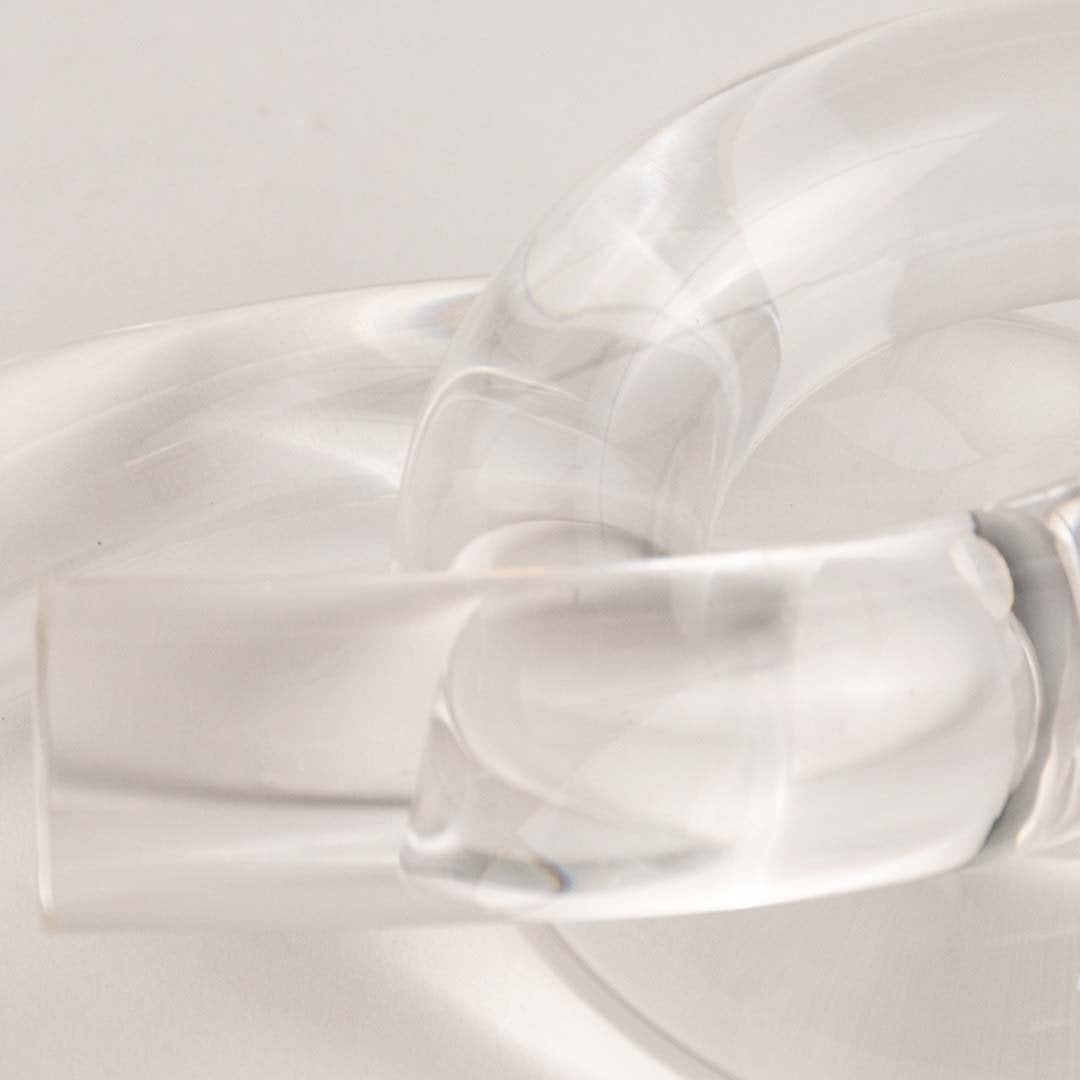 Artistic clear glass knot detail shot highlighting smooth curves and reflective crystal quality.
