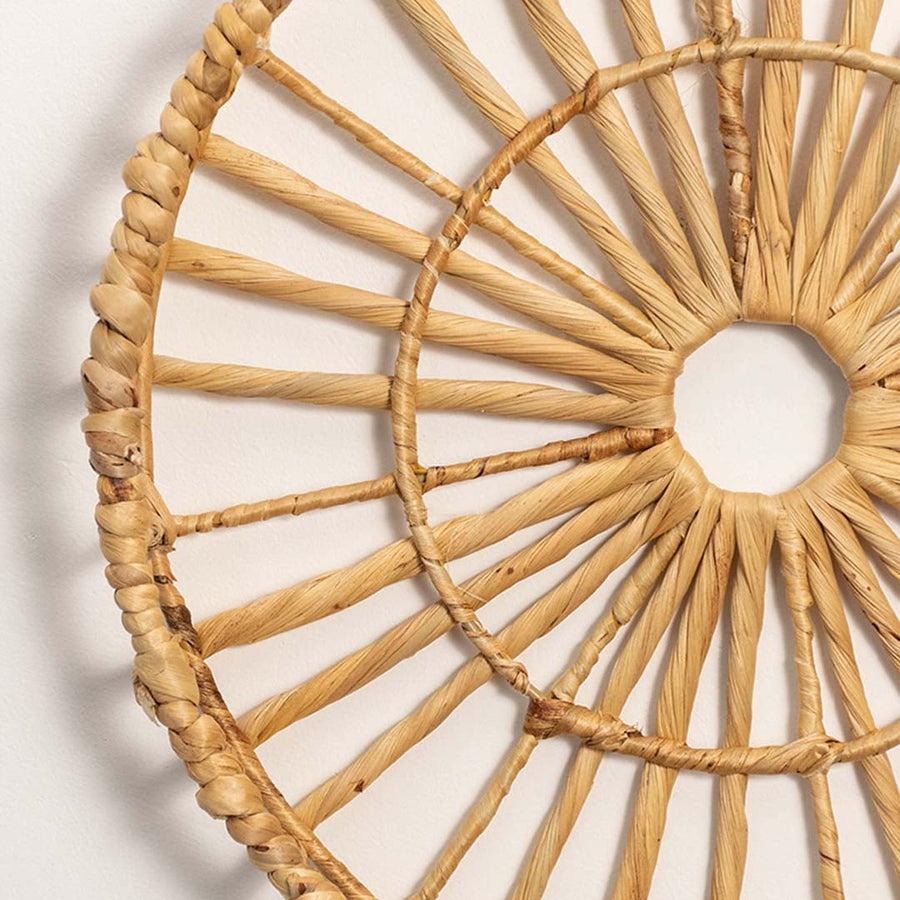 Closeup image of handwoven natural fiber wall decor highlighting detailed radial weaving pattern and organic texture on a clean white background.
