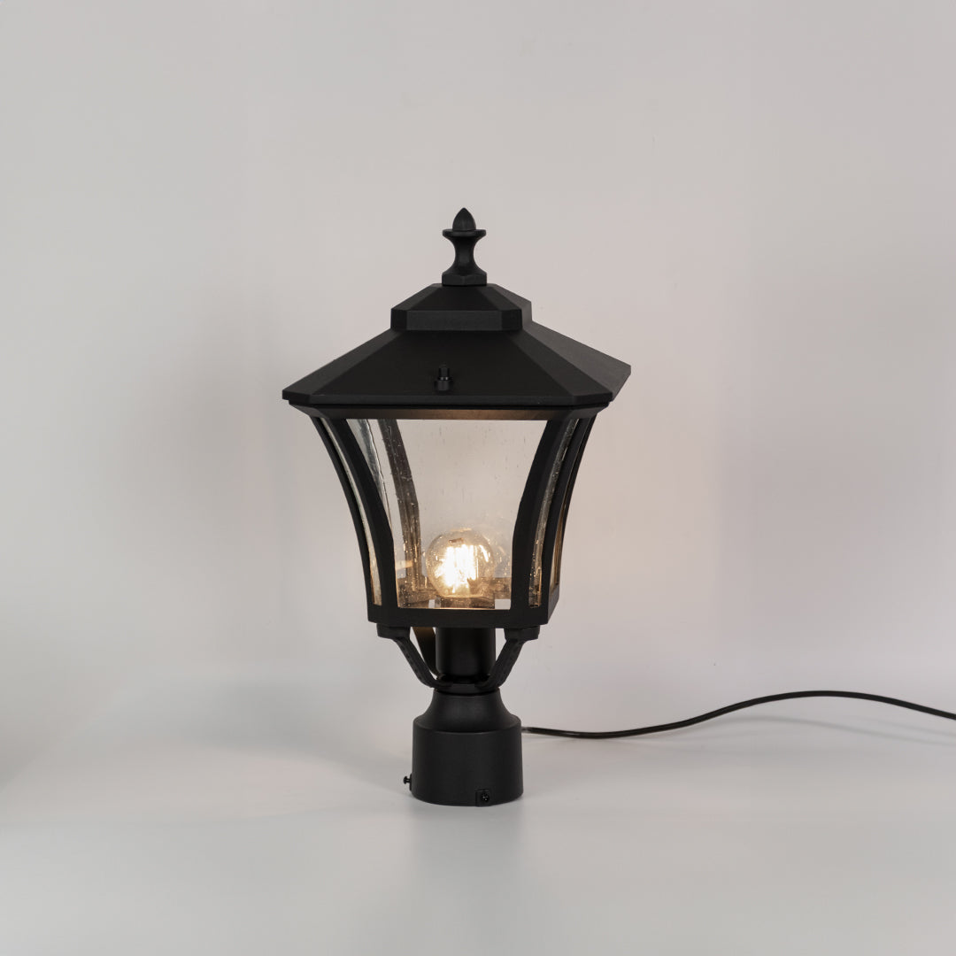 Vintage black outdoor gate light with warm glowing bulb for elegant exterior decor styling use.