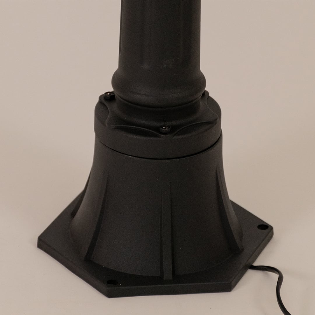 Detailed close up of black aluminum post lamp base showing textured metal pole and ornamental mounting hardware design.