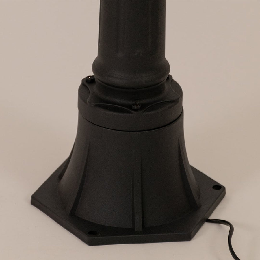 Detailed close up of black aluminum post lamp base showing textured metal pole and ornamental mounting hardware design.