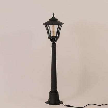 Classic black metal outdoor post light fixture with clear glass lantern switched off on minimal white backdrop.