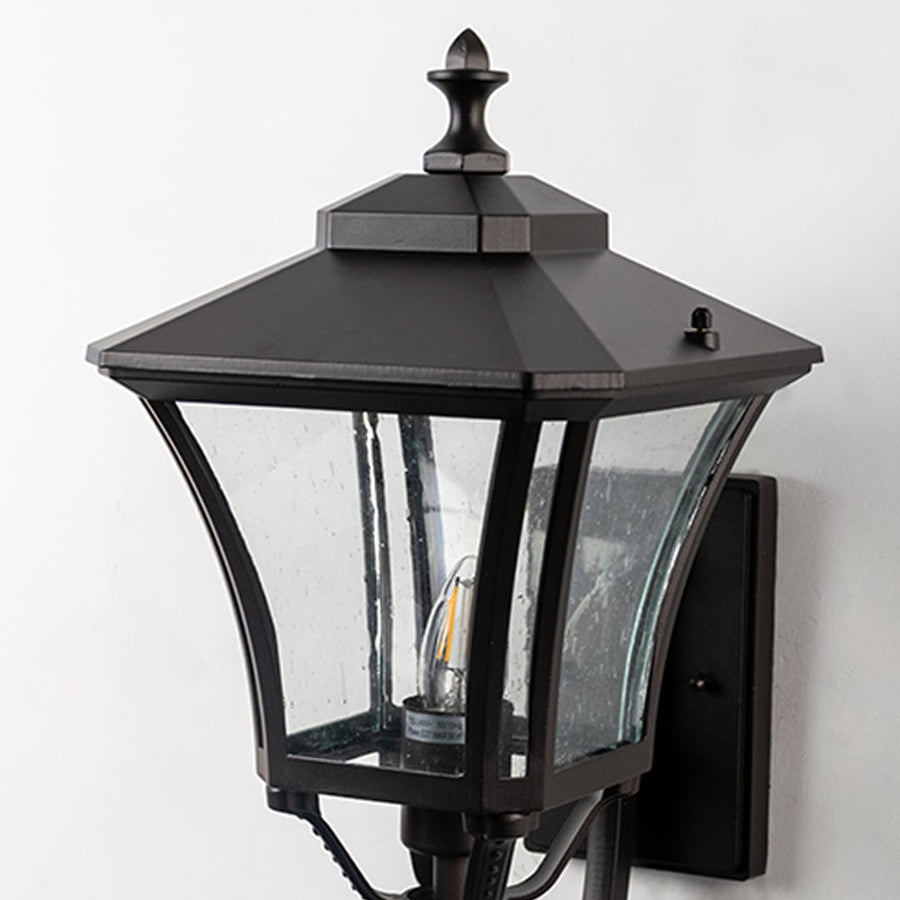 Closeup of outdoor wall lantern with black metal frame and clear glass panels showing classic design and durable exterior build quality.