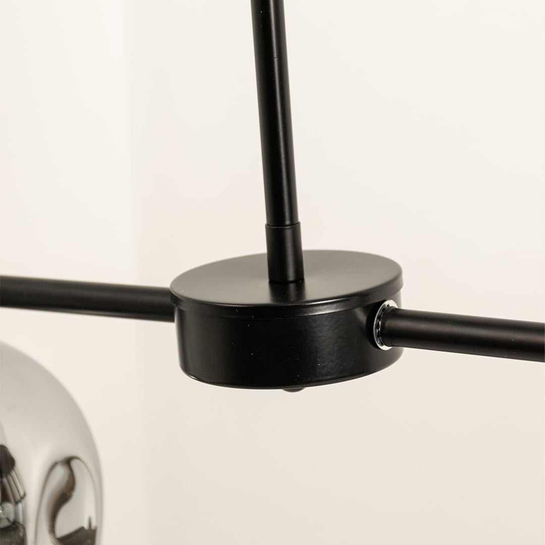 Close view of chrome glass chandelier showing glossy metallic finish black metal rod and detailed modern craftsmanship quality.