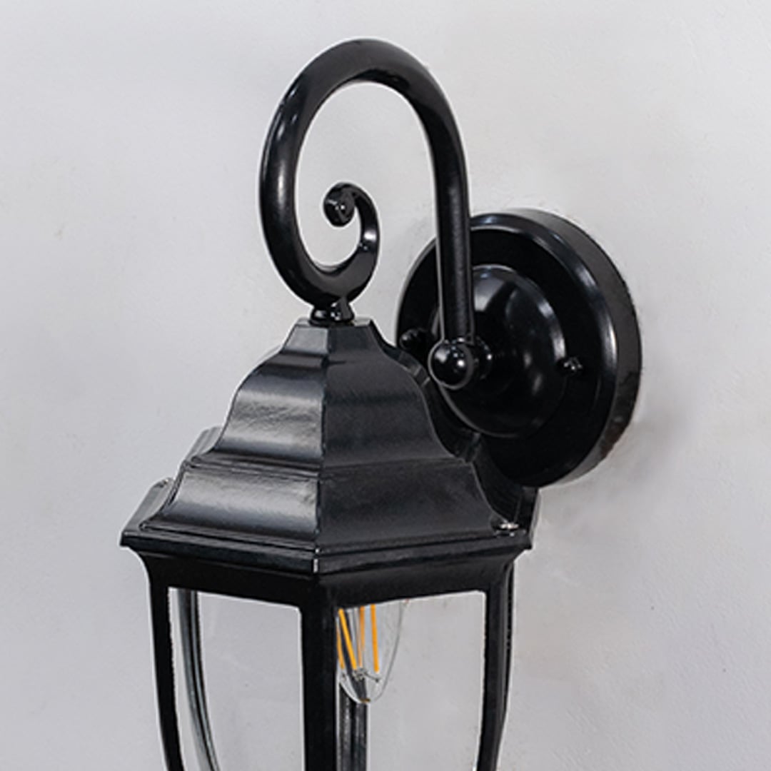 Detailed closeup of lantern wall light showing black metal frame and clear glass design for outdoor lighting.