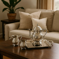 Luxurious silver plated tea set with intricate floral engraving arranged on a granite kitchen counter for elegant high tea serving.