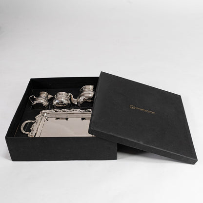Complete silver tea set displayed on white background highlighting intricate engravings and polished metallic shine.