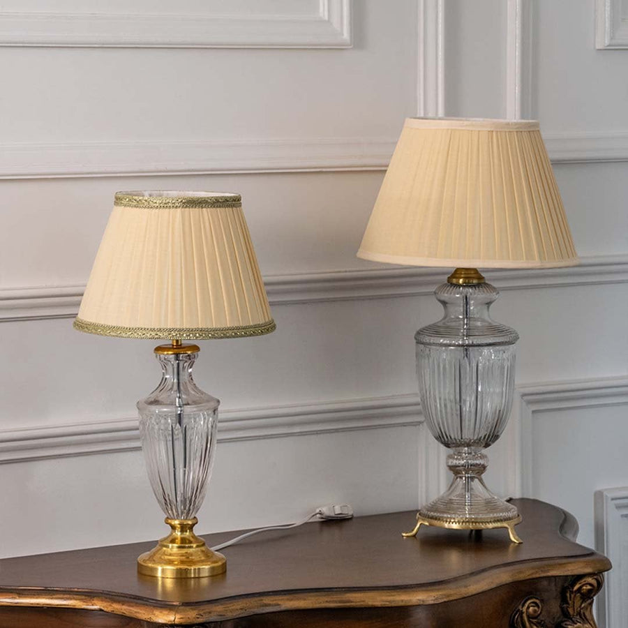 Set of two glass table lamps with gold accents and pleated shades turned off displayed on wooden console showcasing sophisticated living room style.