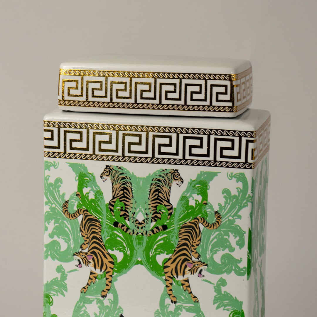 Closeup of white ceramic jar showing detailed tiger motifs and gold geometric patterns.