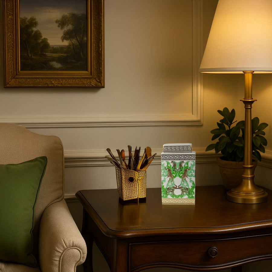 White ceramic jar with gold and green tiger design adding a luxurious accent to a classic wooden side table.