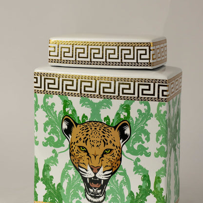 Closeup of white ceramic jar showing fine gold edging and detailed green foliage surrounding a leopard face.