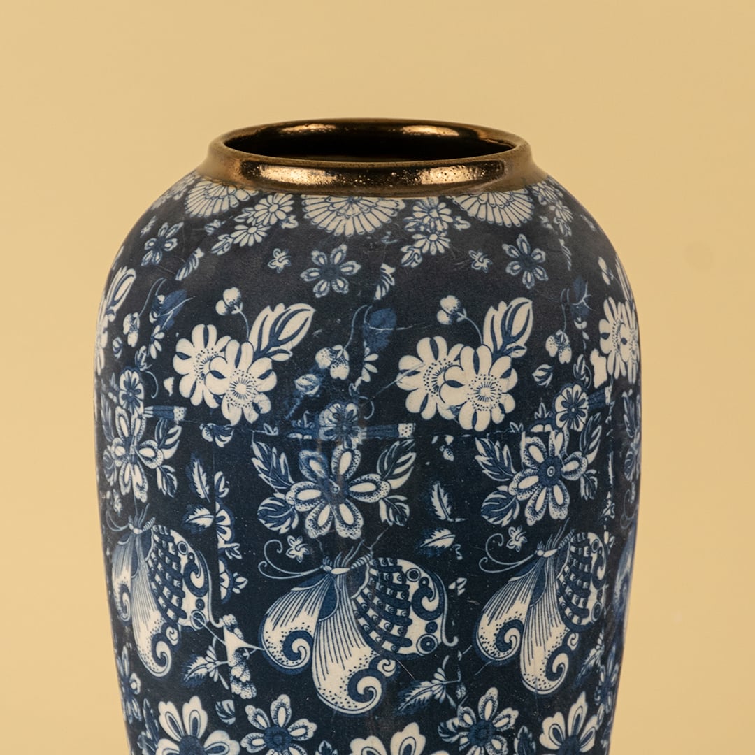 Artistic ceramic vase in deep blue with white hand painted floral motifs and golden rim finish for timeless decor.