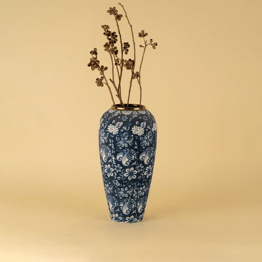 Tall blue ceramic vase with white floral pattern and gold rim styled with dry stems for elegant living room decor.