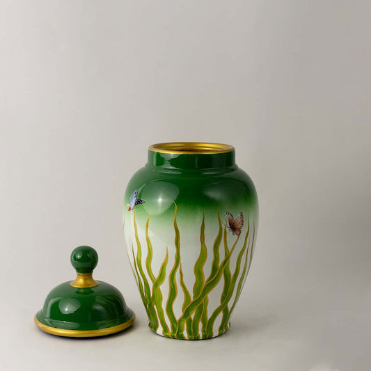 Green ceramic jar with gradient leaf pattern and lid placed on white surface against neutral background showcasing nature inspired modern home decor styling.