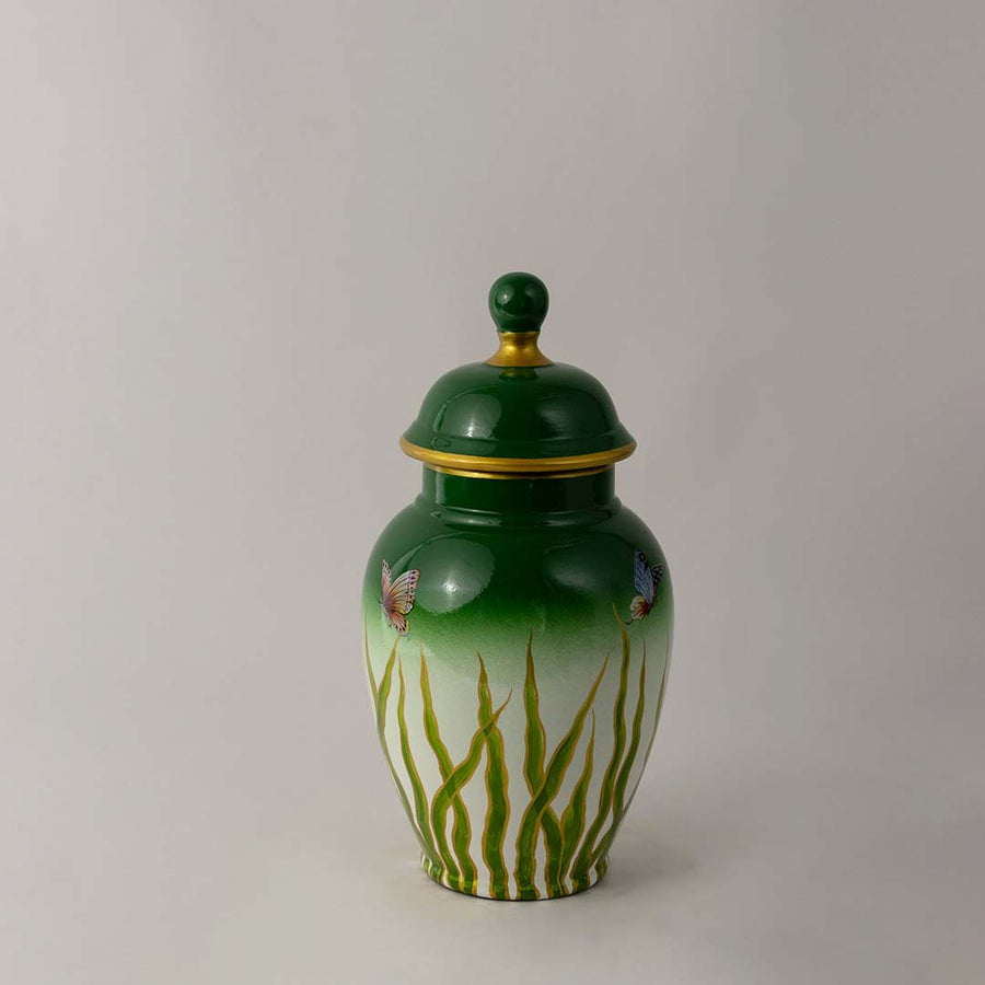Green ceramic jar with glossy finish and lid placed on white surface against neutral background enhancing vibrant decorative home decor aesthetic.