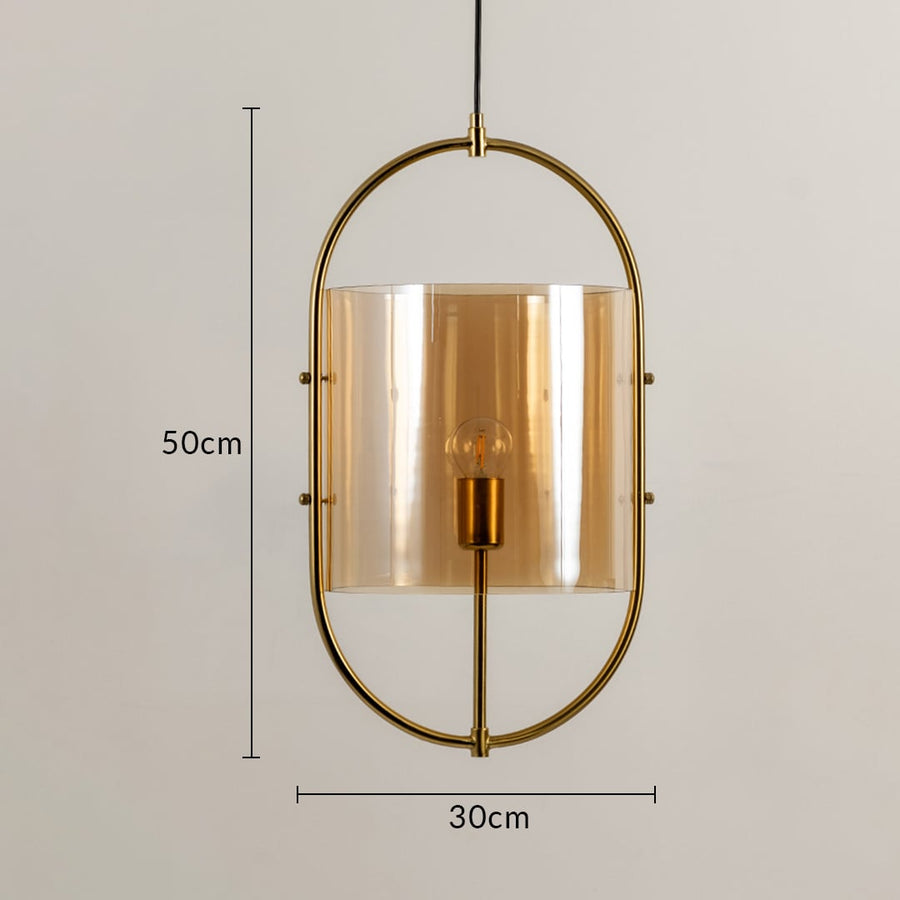Gold pendant light with an oval metal frame and tinted amber glass shade measuring 50 cm in height and 30 cm in width featuring a visible bulb.