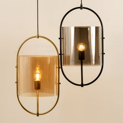 Close-up of a contemporary set of two pendant lights with oval frames in gold and black  featuring tinted glass shades softly glowing.