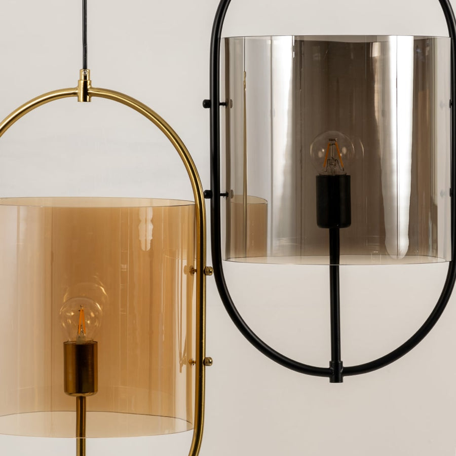 Close-up of modern pendant hanging lights with oval metal frames and tinted glass shades in amber and chrome finishes for any space.
