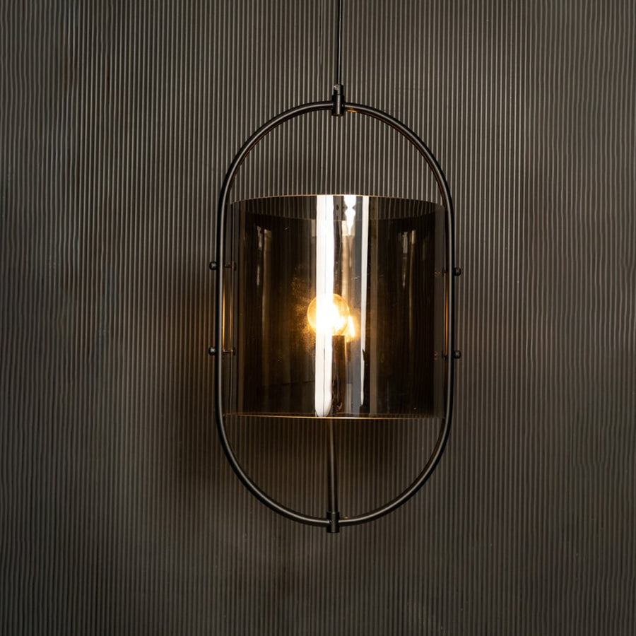 Illuminated pendant showcasing a striking contrast between the black metal frame and smoked glass against a dark backdrop.