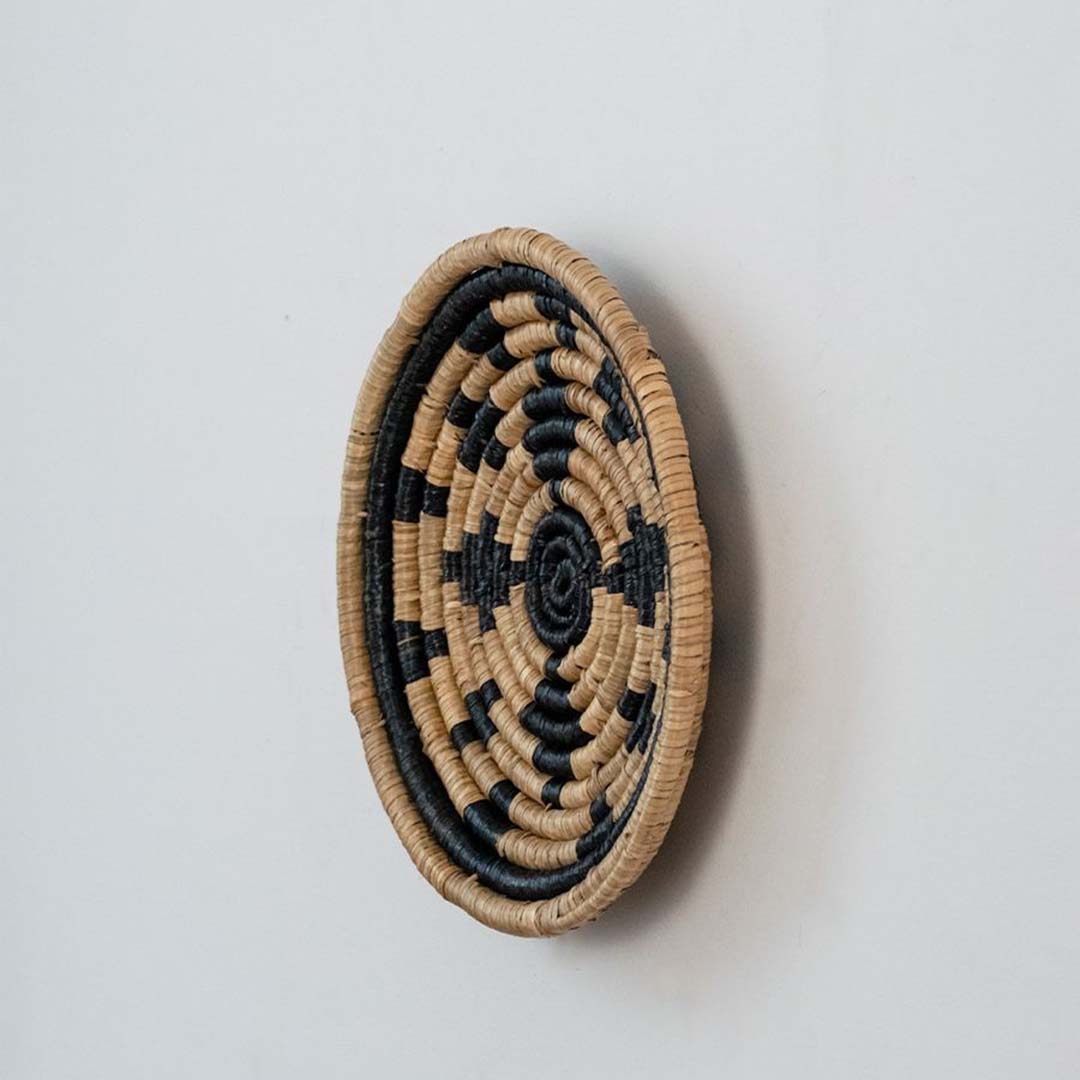 Decorative wicker wall hanging basket in natural beige and black tones for rustic and bohemian wall styling.