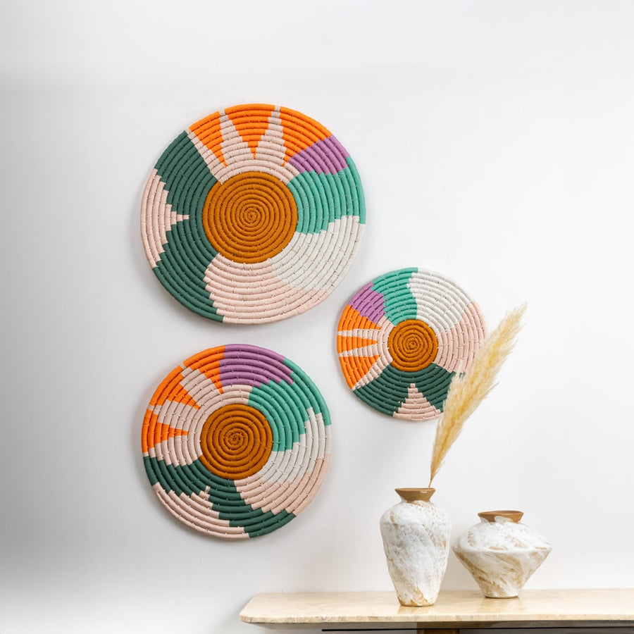 Handwoven multicolor cotton wall plates in green orange pink and cream tones styled on a bright wall for modern lifestyle home decor and artistic wall styling.