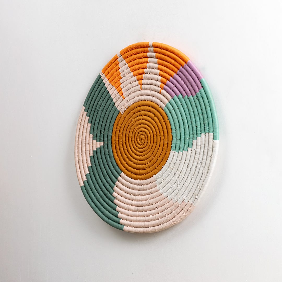 Multicolor cotton wall plate with green orange pink and cream details captured from a side angle on a dark background for bold modern decorative wall styling.