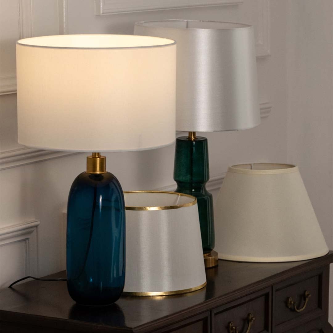 White shade teal glass table lamp on wooden sideboard with light off for fresh modern home décor styling.