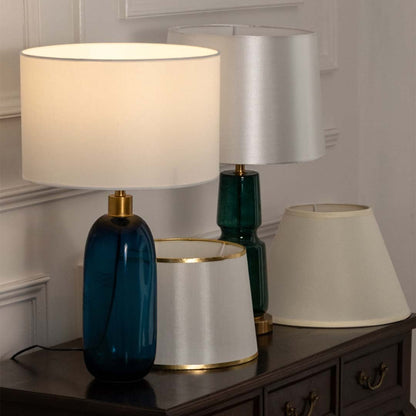 White shade teal glass table lamp on wooden sideboard with light off for fresh modern home décor styling.