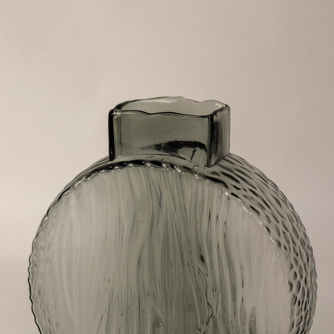 Closeup of smoky gray round glass vase highlighting its intricate wavy pattern and elegant matte glass finish.