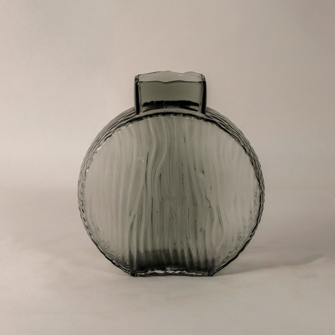 Elegant smoky gray decorative glass vase with round ribbed body and artistic wavy texture shown on white backdrop.