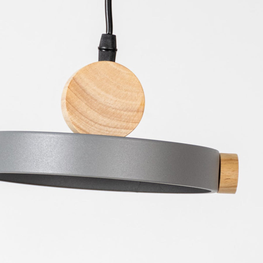 Closeup of wood and metal pendant light with circular round design and black cord for modern home interior lighting.