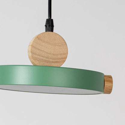 Closeup of green wood and metal pendant light with circular design and black cord for stylish home interior lighting.