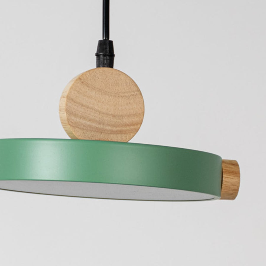 Closeup of green wood and metal pendant light with circular design and black cord for stylish home interior lighting.