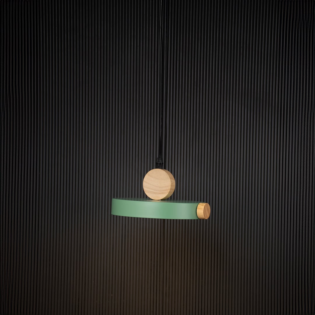 Green wood and metal pendant light glowing on black background with circular design for modern minimalist decor.