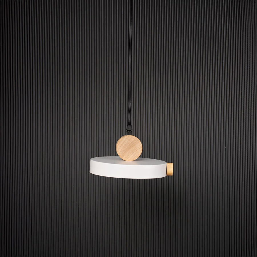 Modern pendant light with flat round shade and wood detail bulb off on black background for stylish home interiors.
