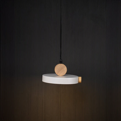 Modern pendant light with flat round shade and natural wood design glowing on black background for stylish interiors.