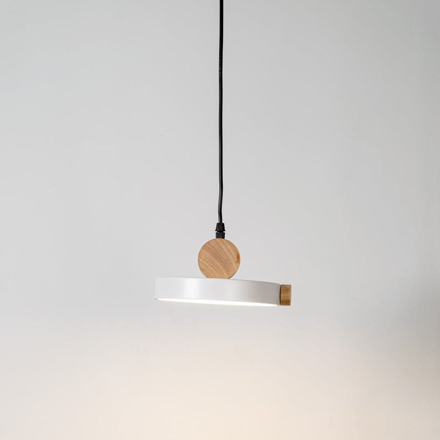 Pendant light glowing on white background with round flat metal shade and natural wood accents for modern interiors.