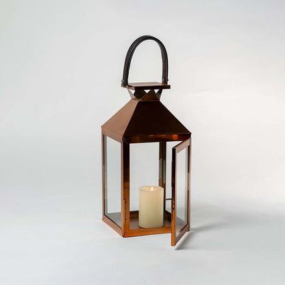 Copper metal lantern with clear glass panels and candle holder for farmhouse tabletop decor styling.