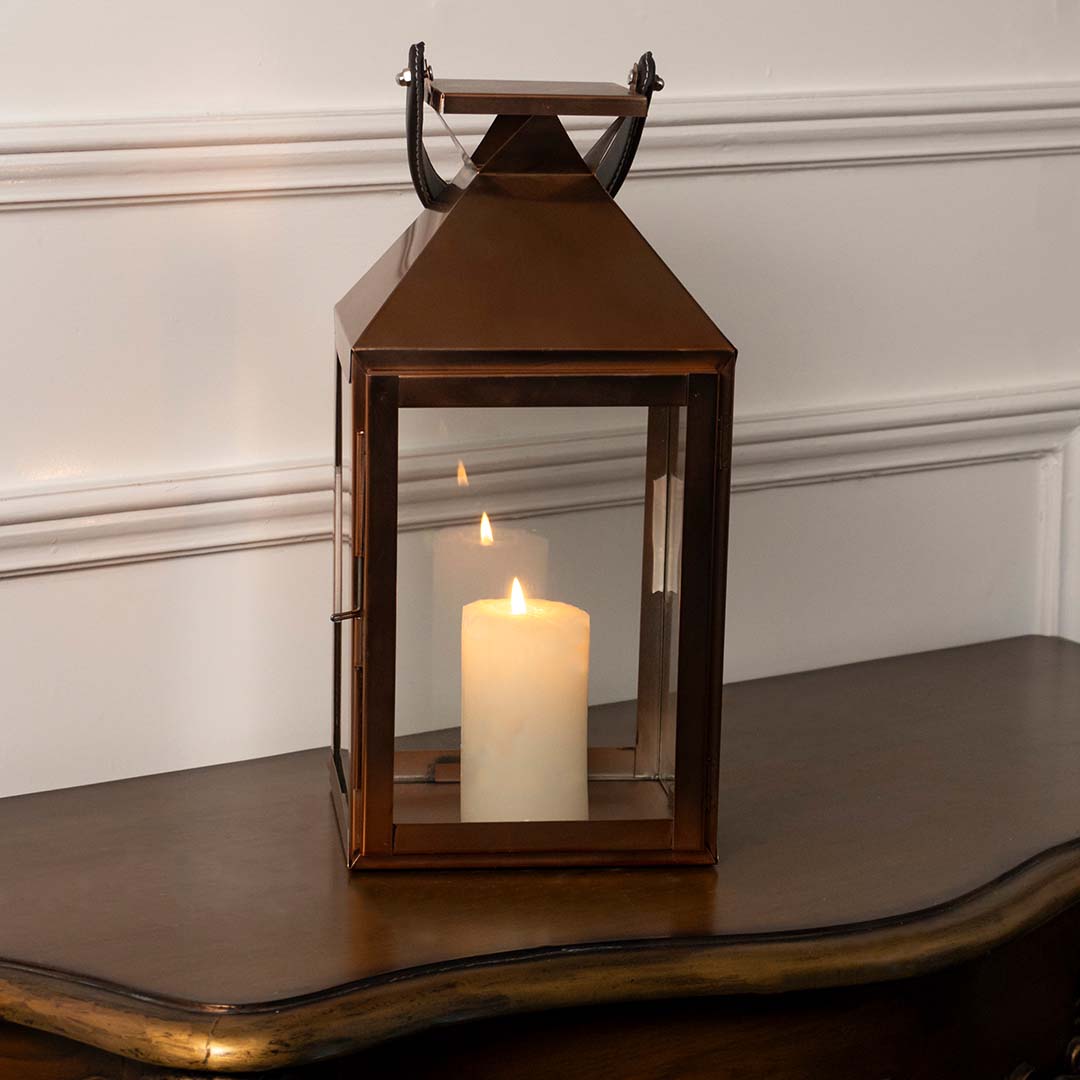 Lantern shown lit against a plain white background showcasing the bronze metallic tone angular roof design and sturdy base construction with precision.