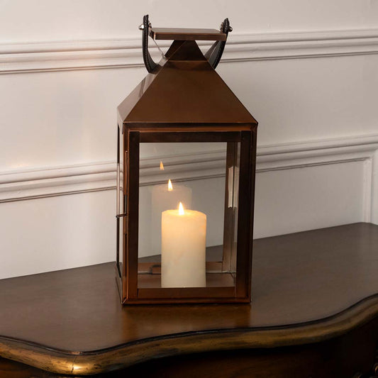 Lantern shown lit against a plain white background showcasing the bronze metallic tone angular roof design and sturdy base construction with precision.