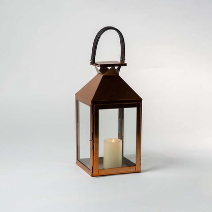 Bronze lantern with glass panels photographed against a white background with door open to reveal interior candle space highlighting product craftsmanship and metallic finish.