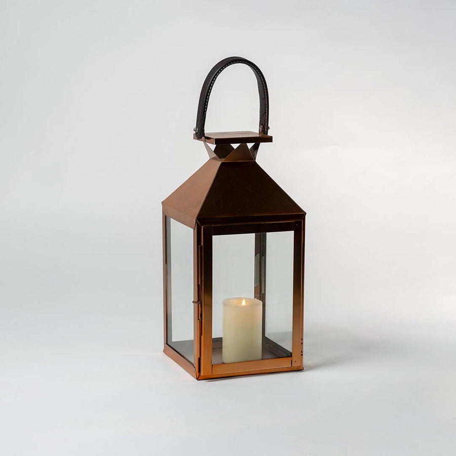 Bronze lantern with glass panels photographed against a white background with door open to reveal interior candle space highlighting product craftsmanship and metallic finish.