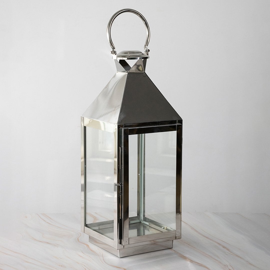 Tall stainless steel lantern turned off shown plain on white background highlighting polished finish.