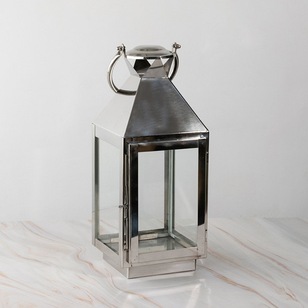 Stainless steel lantern turned off displayed plain on white background highlighting polished finish.