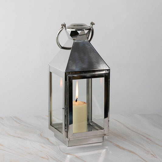 Stainless steel lantern lit displayed plain on white background highlighting polished finish.