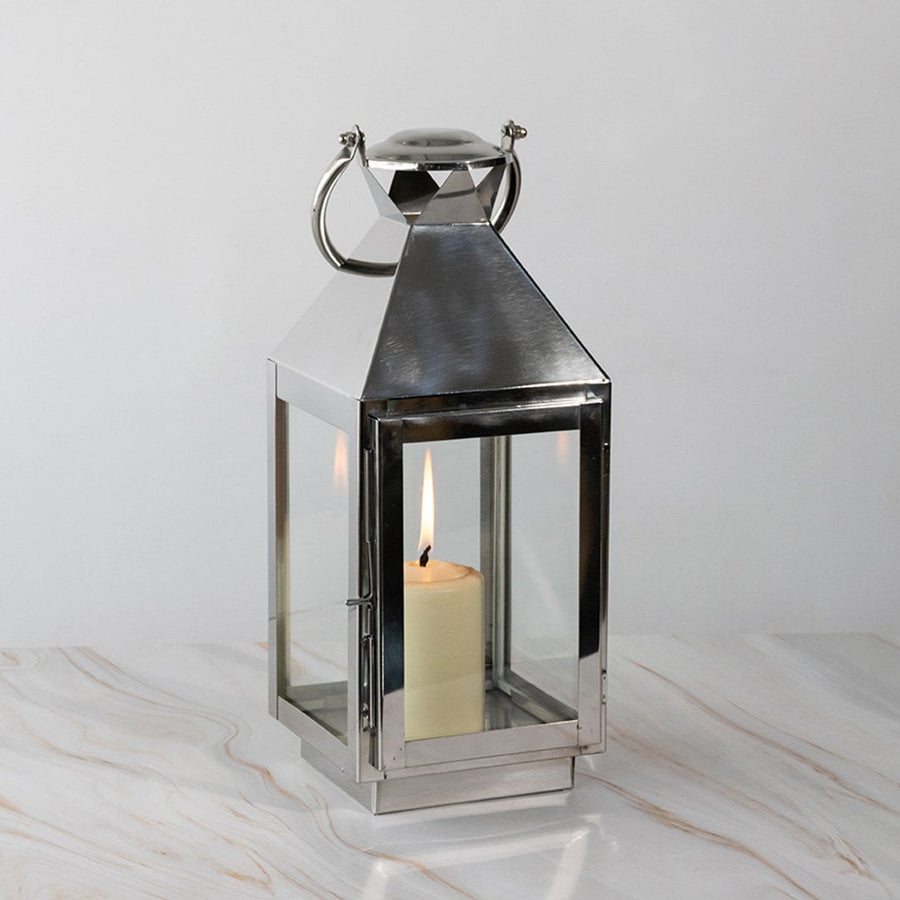 Stainless steel lantern lit displayed plain on white background highlighting polished finish.