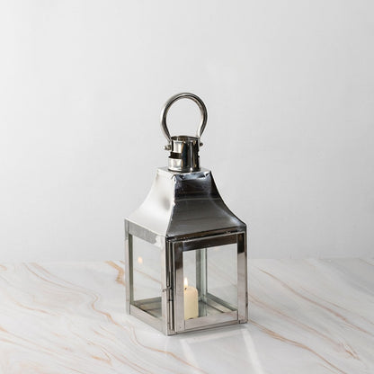 Silver lantern lit shown plain on white background highlighting polished stainless steel frame.