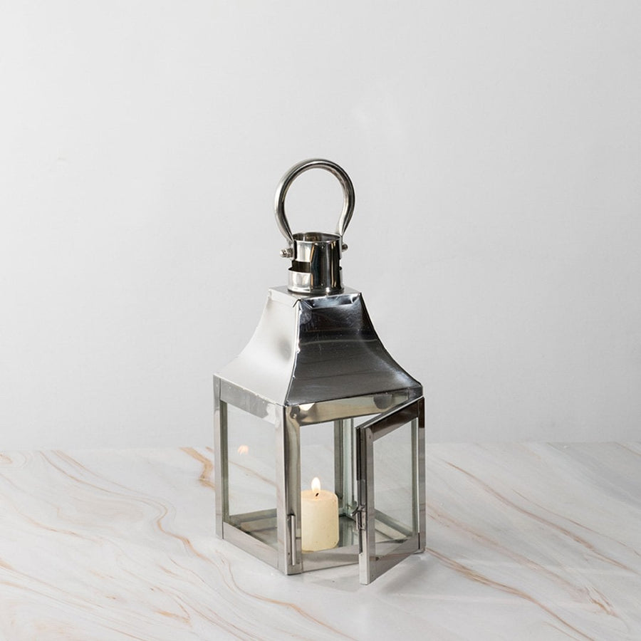 Stainless steel lantern with candle lit displayed on white background for modern home and garden decor.