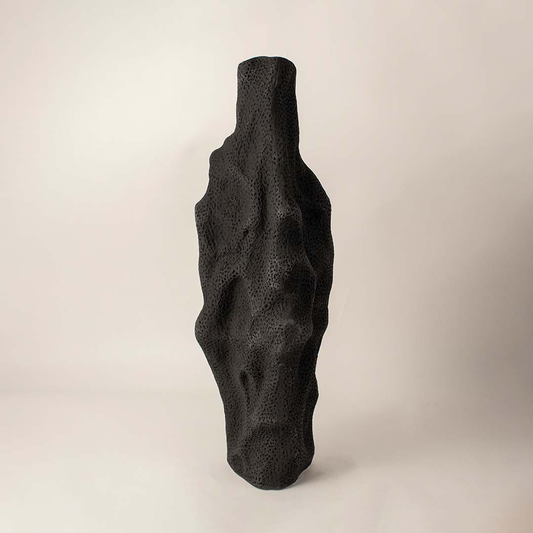 Matte black sculptural ceramic vase with organic texture standing on white background showcasing artistic handmade design.