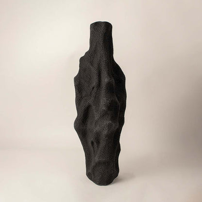 Matte black sculptural ceramic vase with organic texture standing on white background showcasing artistic handmade design.